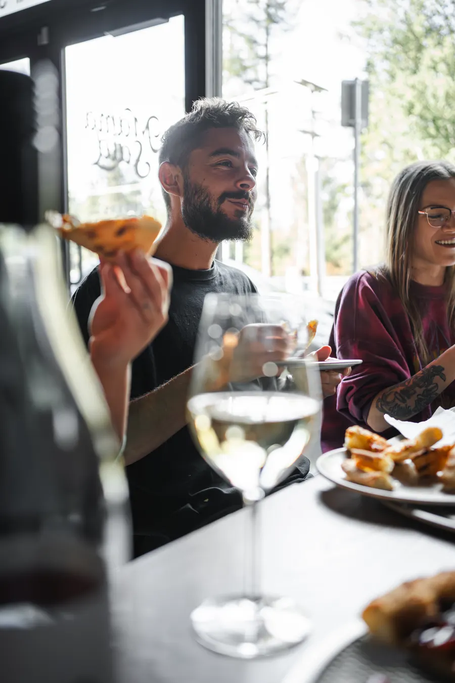 Guests sharing pizza and wine by the window