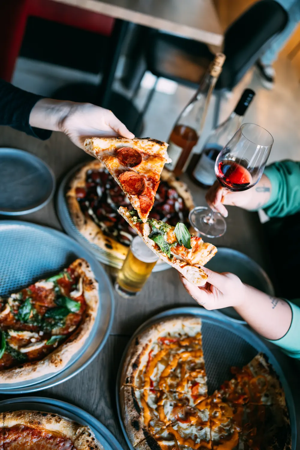 Friends cheersing wine over pizzas at Mama Said