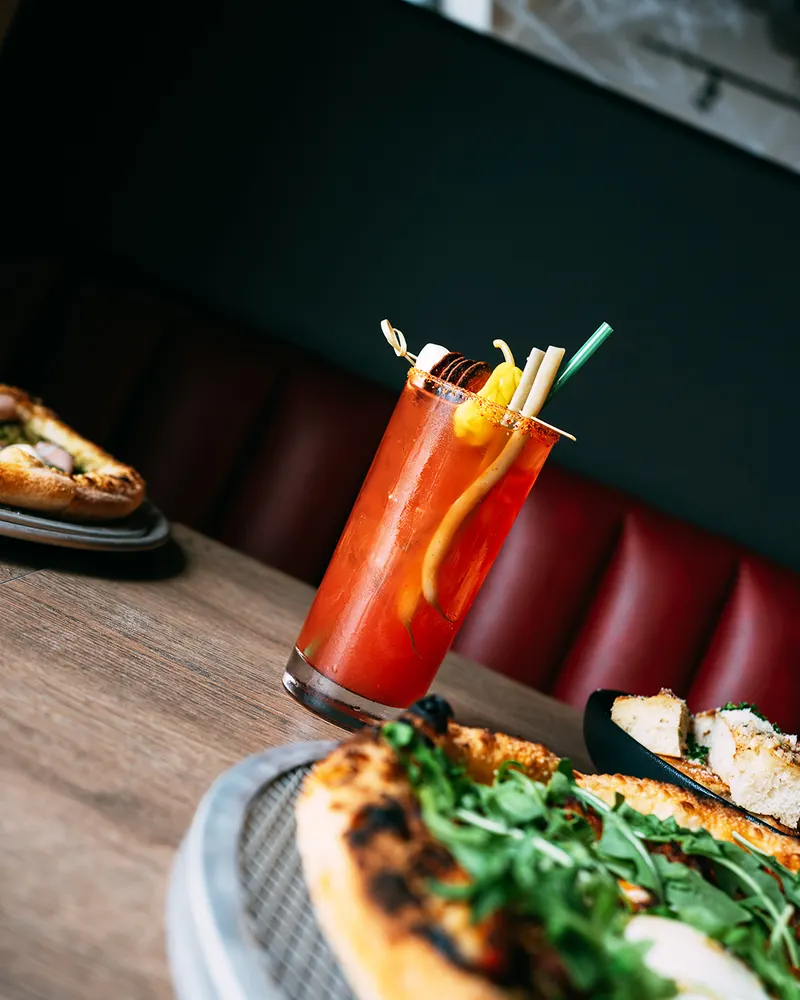 Pizza Caesar cocktail beside a fresh pie