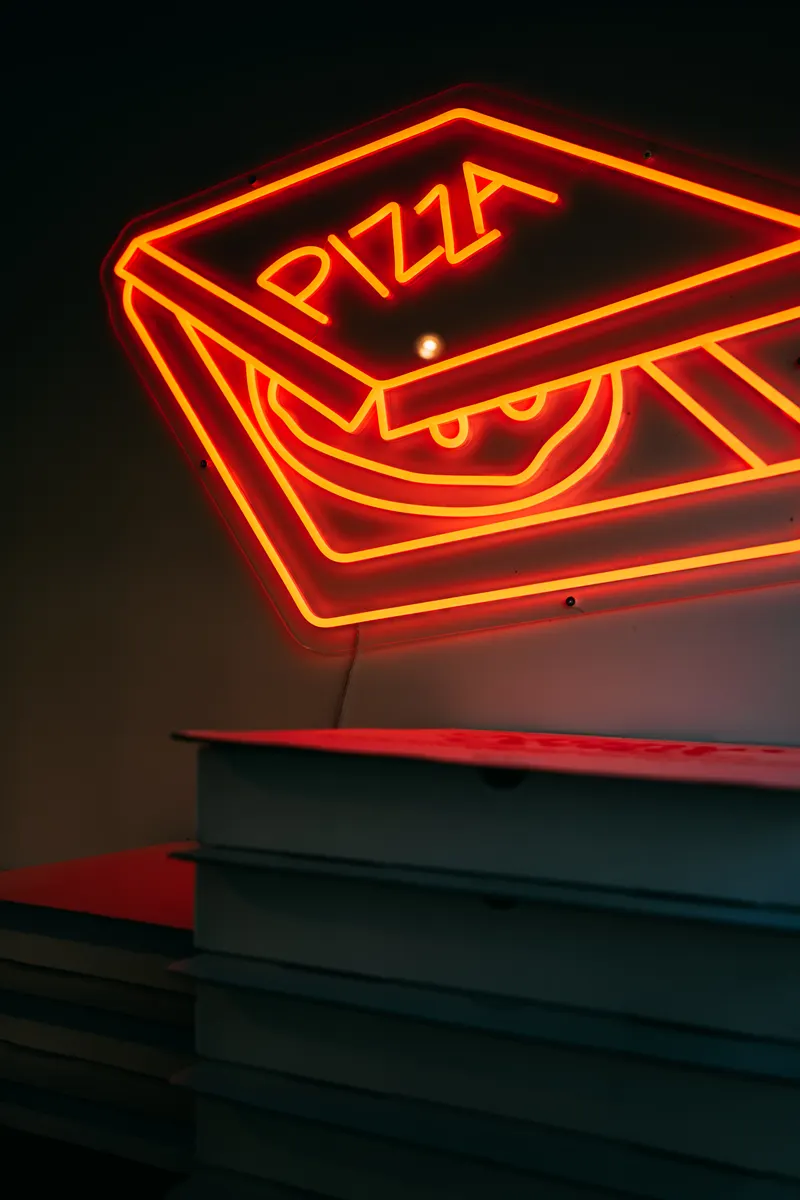 Neon pizza box sign glowing in the dining room